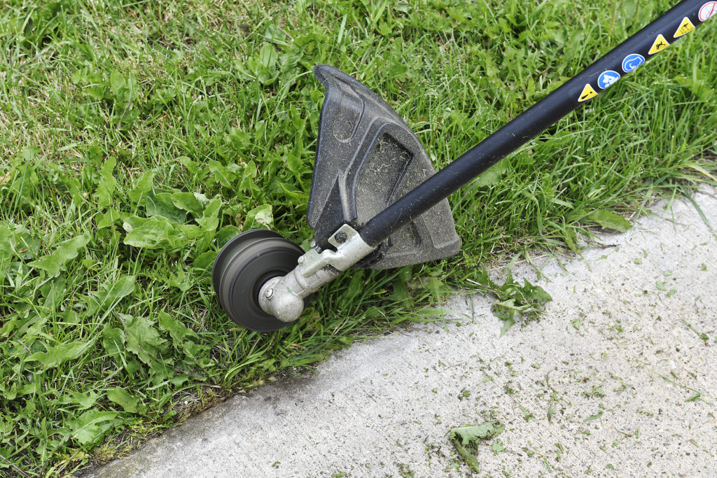 String trimmer edging along a sidewalk
