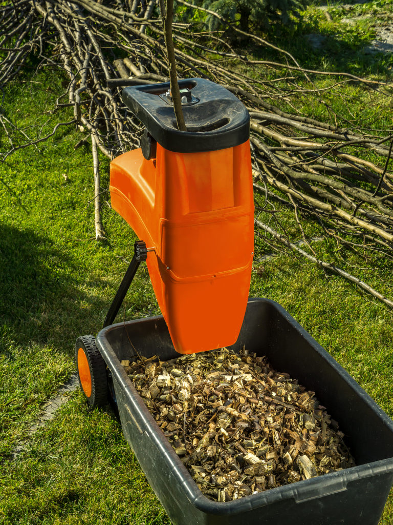 Electric wood shredder with wood chips used for garden mulching.